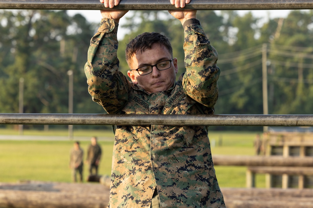 Marines with Marine Corps Combat Service Support Schools maneuver through an obstacle course