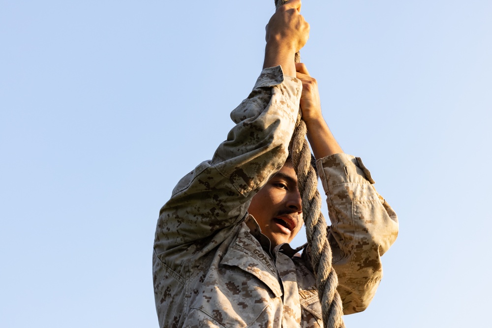 Marines with Marine Corps Combat Service Support Schools maneuver through an obstacle course