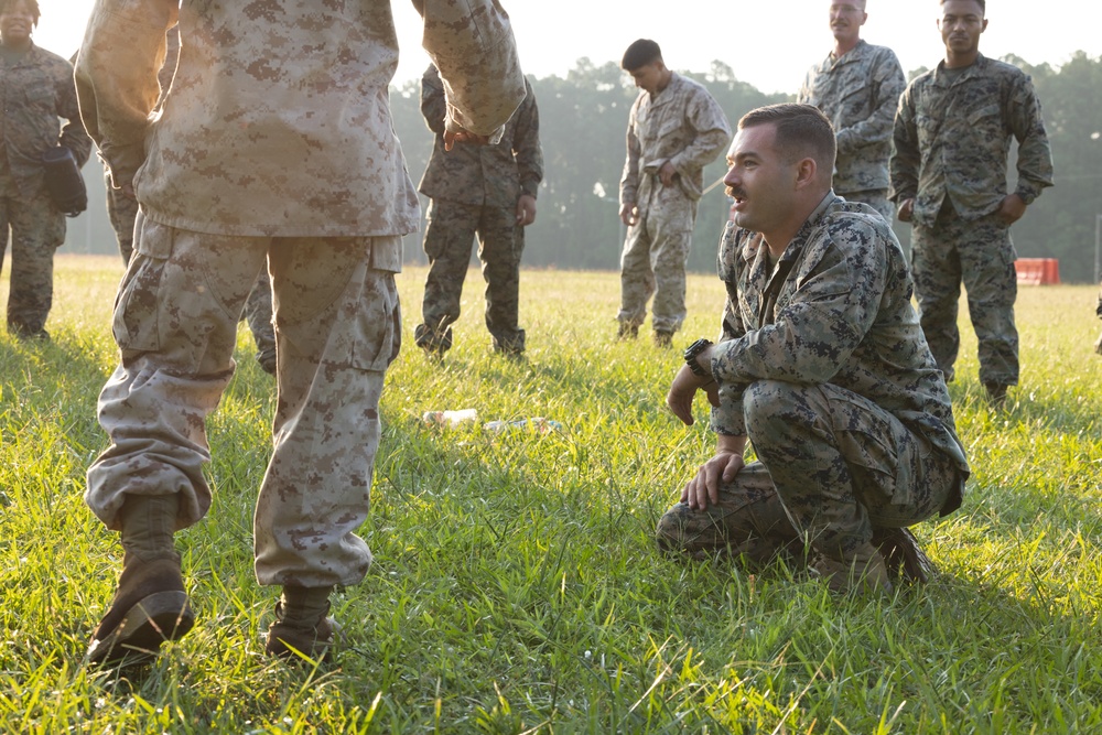 Marines with Marine Corps Combat Service Support Schools maneuver through an obstacle course