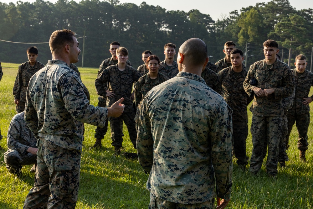 Marines with Marine Corps Combat Service Support Schools maneuver through an obstacle course