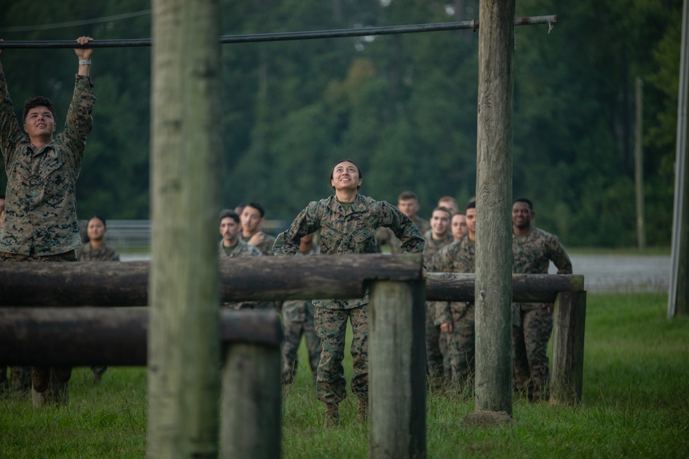 Marines with Marine Corps Combat Service Support Schools maneuver through an obstacle course