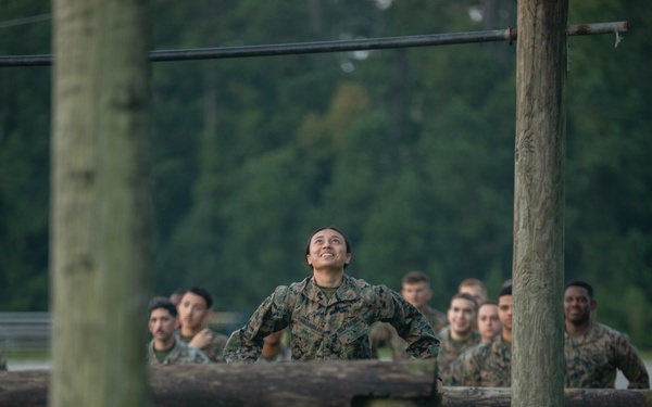 Marines with Marine Corps Combat Service Support Schools maneuver through an obstacle course