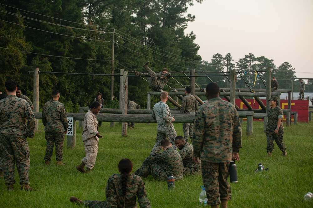 Marines with Marine Corps Combat Service Support Schools maneuver through an obstacle course