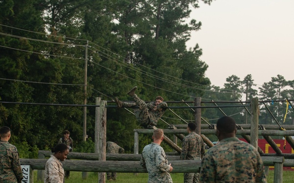 Marines with Marine Corps Combat Service Support Schools maneuver through an obstacle course