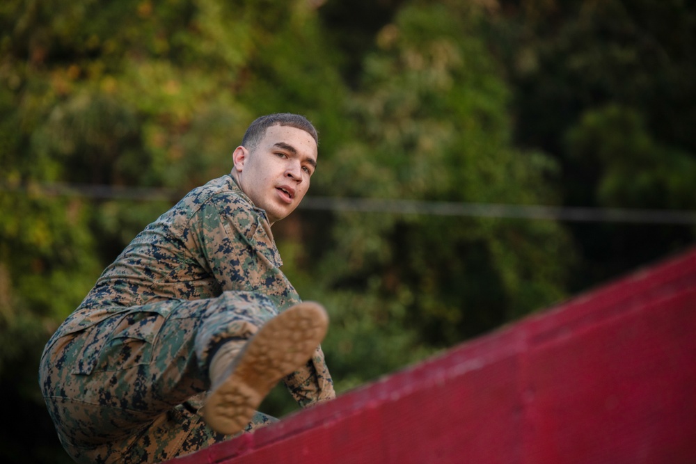 Marines with Marine Corps Combat Service Support Schools maneuver through an obstacle course