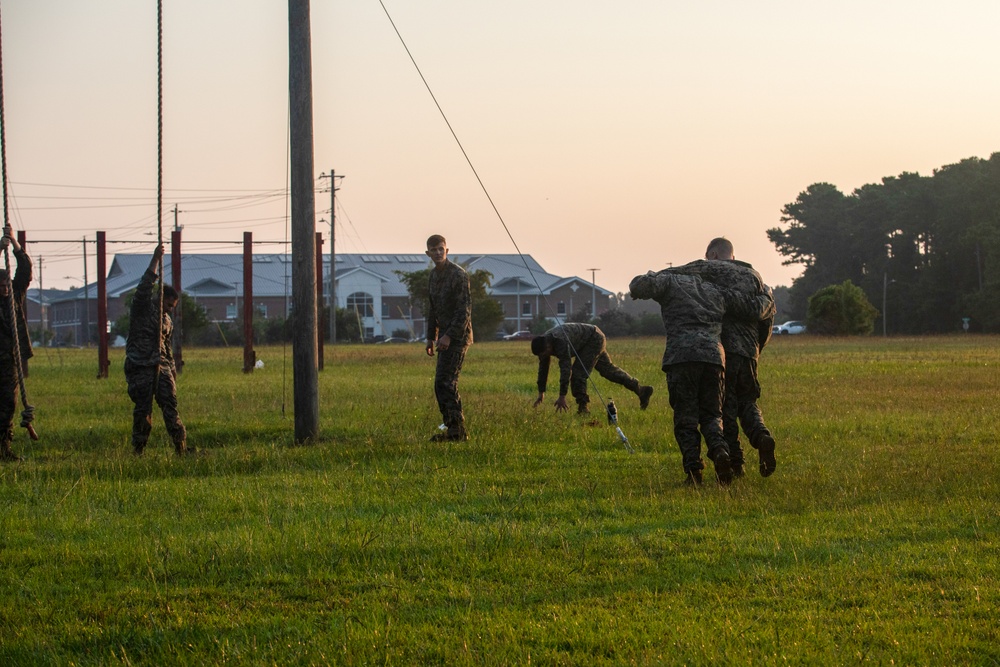 Marines with Marine Corps Combat Service Support Schools maneuver through an obstacle course