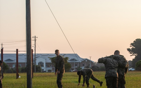 Marines with Marine Corps Combat Service Support Schools maneuver through an obstacle course