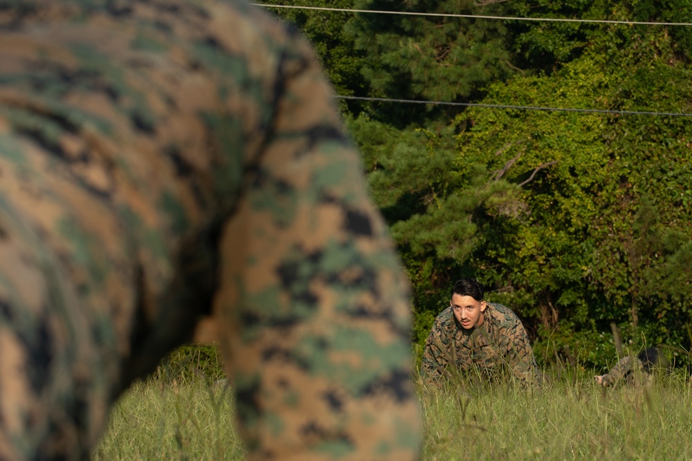 Marines with Marine Corps Combat Service Support Schools maneuver through an obstacle course