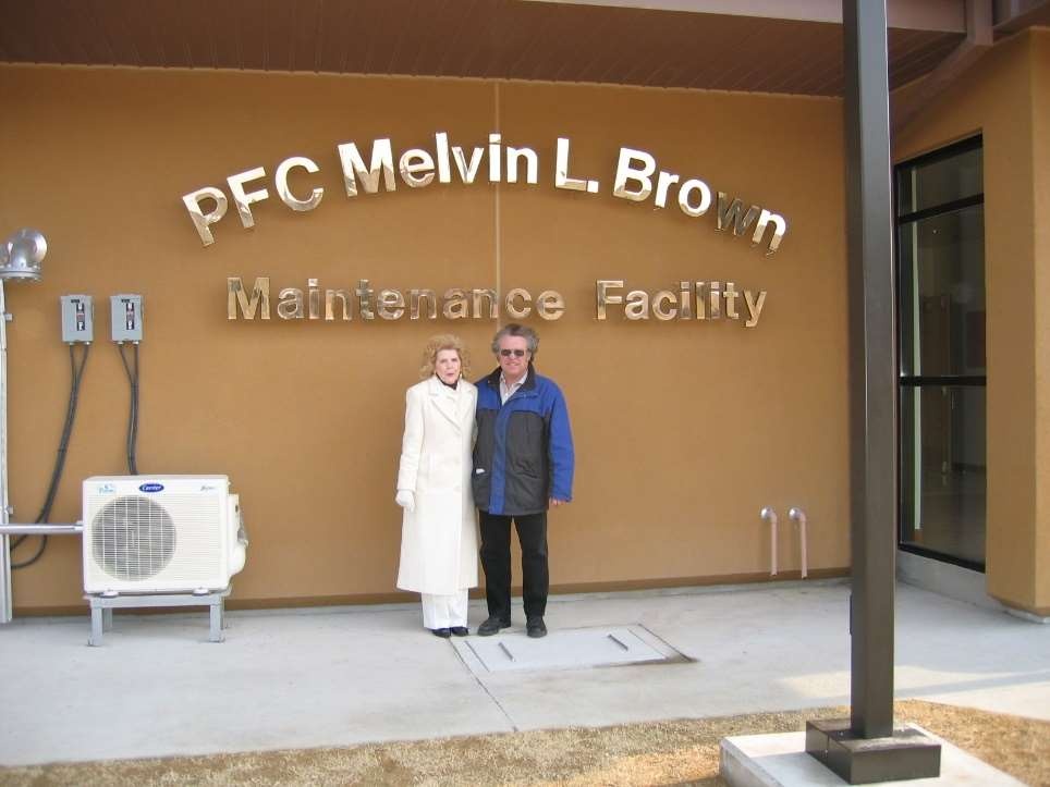 Army Sustainment Command G4 (Logistics) engineer William Ellis (blue coat) with next-of-kin of the Medal of Honor awardee for whom this new Army Prepositioned Stock vehicle maintenance shop was named.