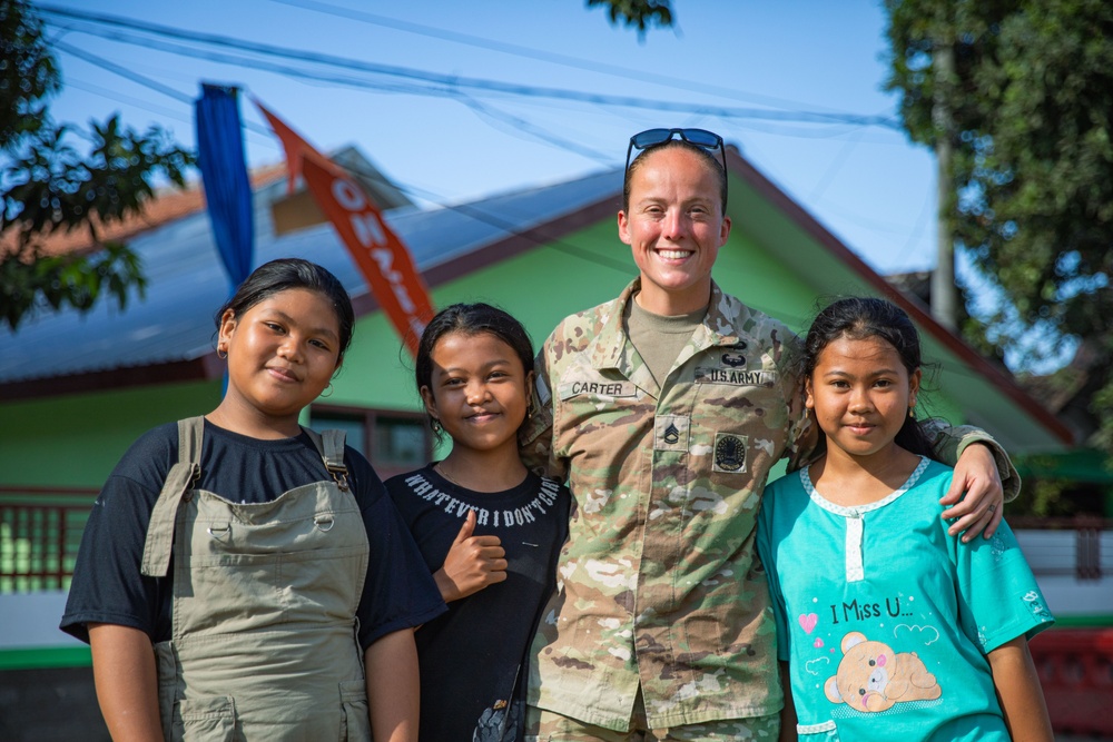 U.S. Army Sgt. 1st Class Kelly Carter of the 610th Engineer Support Company, 864th Engineer Battalion, takes a picture with local children during Super Garuda Shield 2024