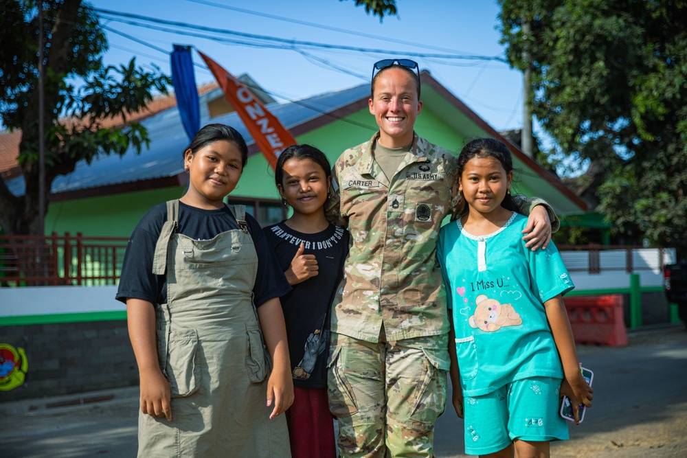 U.S. Army Sgt. 1st Class Kelly Carter, of the 610th Engineer Support Company, 864th Engineer Battalion, takes a picture with local children, Super Garuda Shield 2024