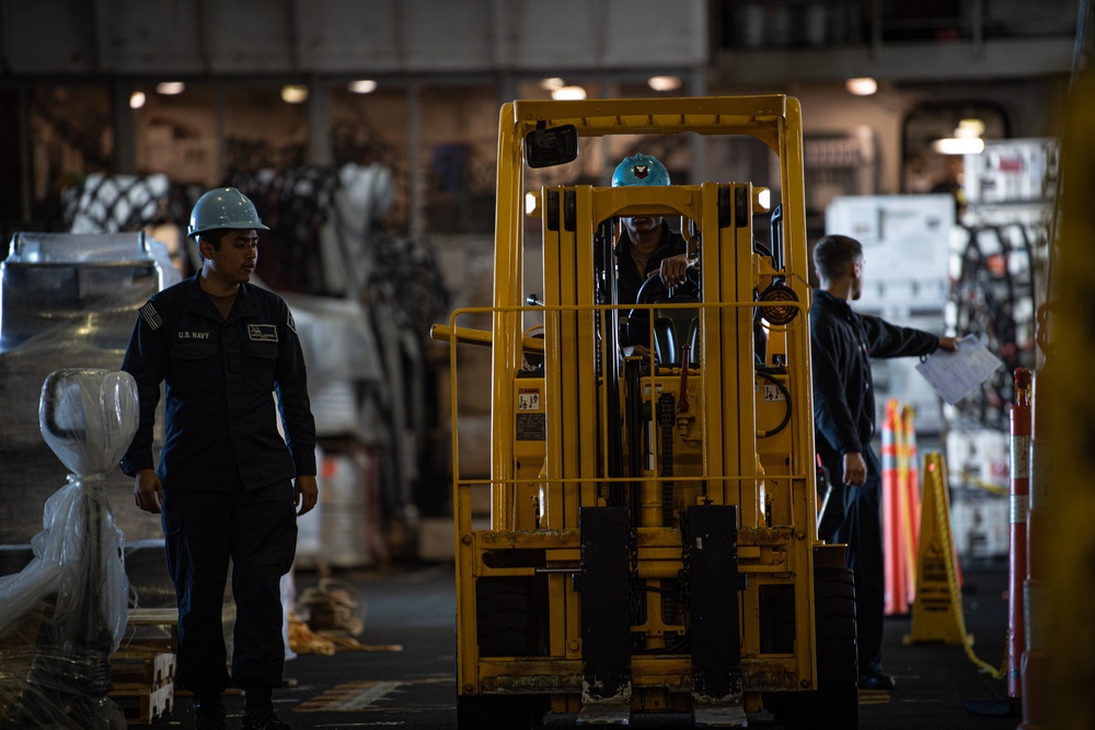 Nimitz Sailors Guide a Forklift Through the Hangar Bay