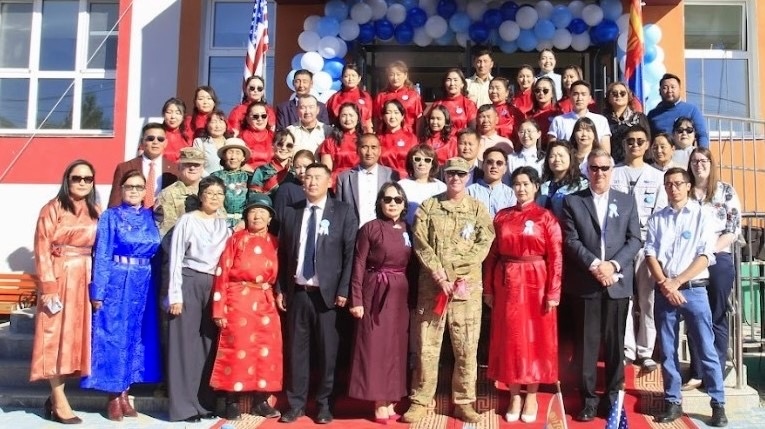 Attendees pose for a photo on the front steps of the new school after the ceremony