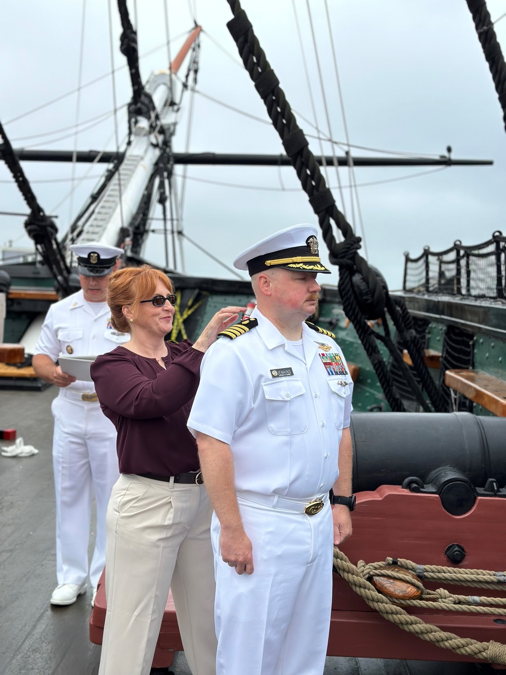 Ms. Amanda Bowman attaches shoulderboards for Captain Jenkins