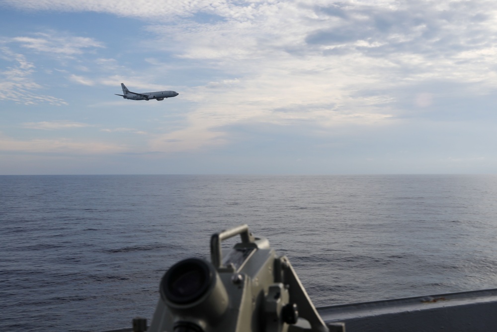 A P-8 Poseidon Maritime Patrol aircraft conducts a fly by USS Howard in the South China Sea