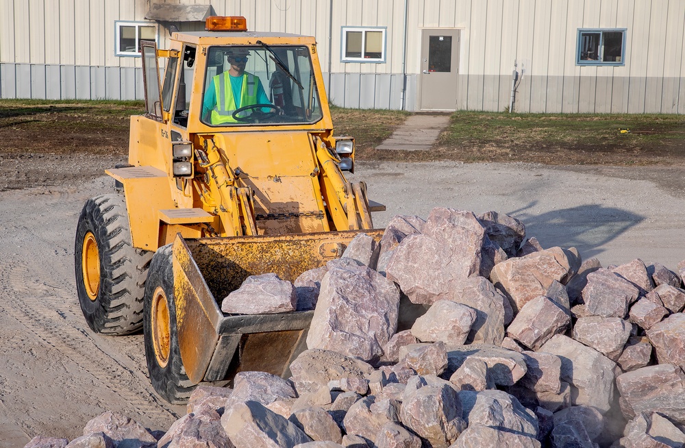 USACE heavy equipment operator scoops riprap along Missouri River