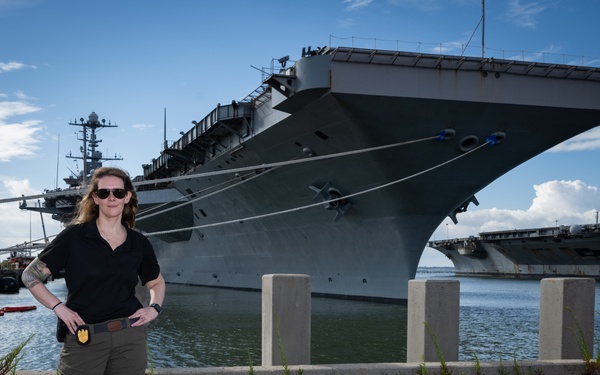 Naval Criminal Investigative Service (NCIS) Special Agent Afloat (SAA) Bernadette Fuffy poses for an environmental portrait in front of the US Navy aircraft carrier USS Harry S. Truman (CVN 75) at Norfolk Naval Station Virginia on 19 September 2024.