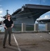 Naval Criminal Investigative Service (NCIS) Special Agent Afloat (SAA) Bernadette Fuffy poses for an environmental portrait in front of the US Navy aircraft carrier USS Harry S. Truman (CVN 75) at Norfolk Naval Station Virginia on 19 September 2024.