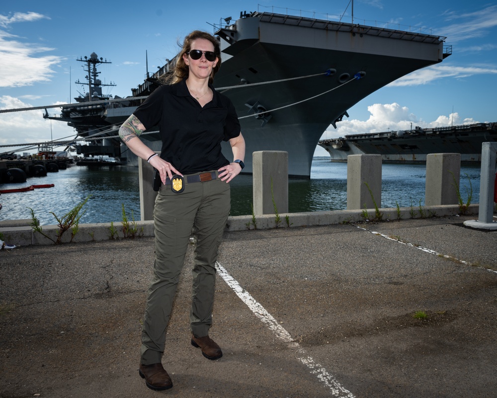 Naval Criminal Investigative Service (NCIS) Special Agent Afloat (SAA) Bernadette Fuffy poses for an environmental portrait in front of the US Navy aircraft carrier USS Harry S. Truman (CVN 75) at Norfolk Naval Station Virginia on 19 September 2024.