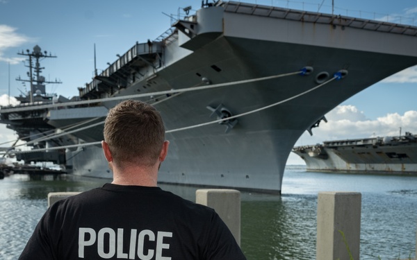 Naval Criminal Investigative Service (NCIS) Special Agent Afloat (SAA) Justin Botkin stand for an environmental portrait in front of the US Navy aircraft carrier USS Harry S. Truman (CVN 75) at Norfolk Naval Station Virginia on 19 September 2024.