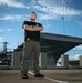 Naval Criminal Investigative Service (NCIS) Special Agent Afloat (SAA) Justin Botkin stand for an environmental portrait in front of the US Navy aircraft carrier USS Harry S. Truman (CVN 75) at Norfolk Naval Station Virginia on 19 September 2024.