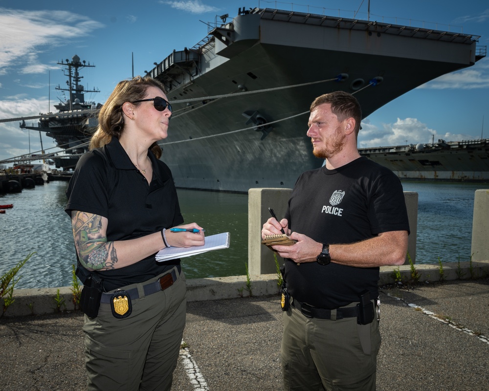 Naval Criminal Investigative Service (NCIS) Special Agents Afloat (SAA) Bernadette Duffy and Justin Botkin discuss an on-going investigation in front of the US Navy aircraft carrier USS Harry S. Truman (CVN 75)