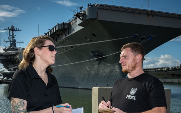 Naval Criminal Investigative Service (NCIS) Special Agents Afloat (SAA) Bernadette Duffy and Justin Botkin discuss an on-going investigation in front of the US Navy aircraft carrier USS Harry S. Truman (CVN 75)