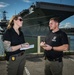 Naval Criminal Investigative Service (NCIS) Special Agents Afloat (SAA) Bernadette Duffy and Justin Botkin discuss an on-going investigation in front of the US Navy aircraft carrier USS Harry S. Truman (CVN 75)