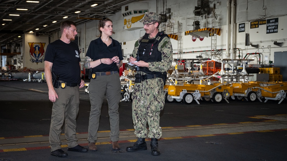 Naval Criminal Investigative Service (NCIS) Special Agents Afloat (SAA) Bernadette Duffy and Justin Botkin talk with Master-at-Arms First Class (MA!) Travis Beckman about an on-going investigation