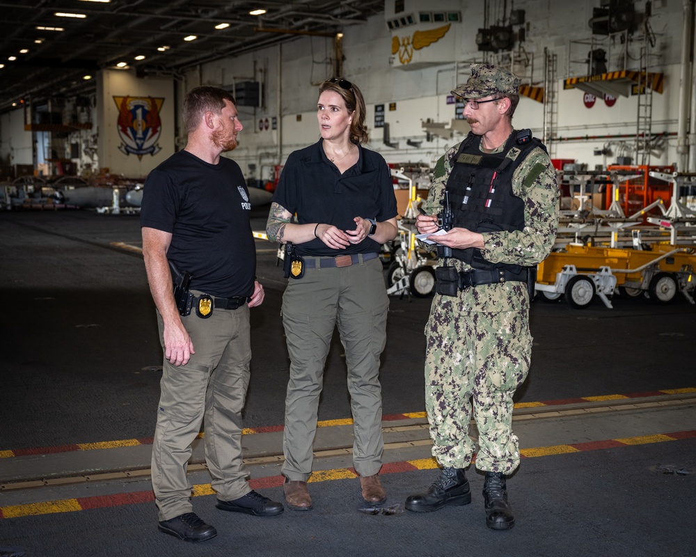 Special Agents Afloat (SAA) Bernadette Duffy and Justin Botkin talk with Master-at-Arms First Class (MA!) Travis Beckman about an on-going investigation in the hangar bay of the aircraft carrier USS Harry S. Truman (CVN 75)