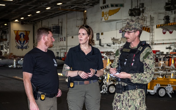 Special Agents Afloat (SAA) Bernadette Duffy and Justin Botkin talk with Master-at-Arms First Class (MA!) Travis Beckman about an on-going investigation in the hangar bay of the aircraft carrier USS Harry S. Truman (CVN 75)