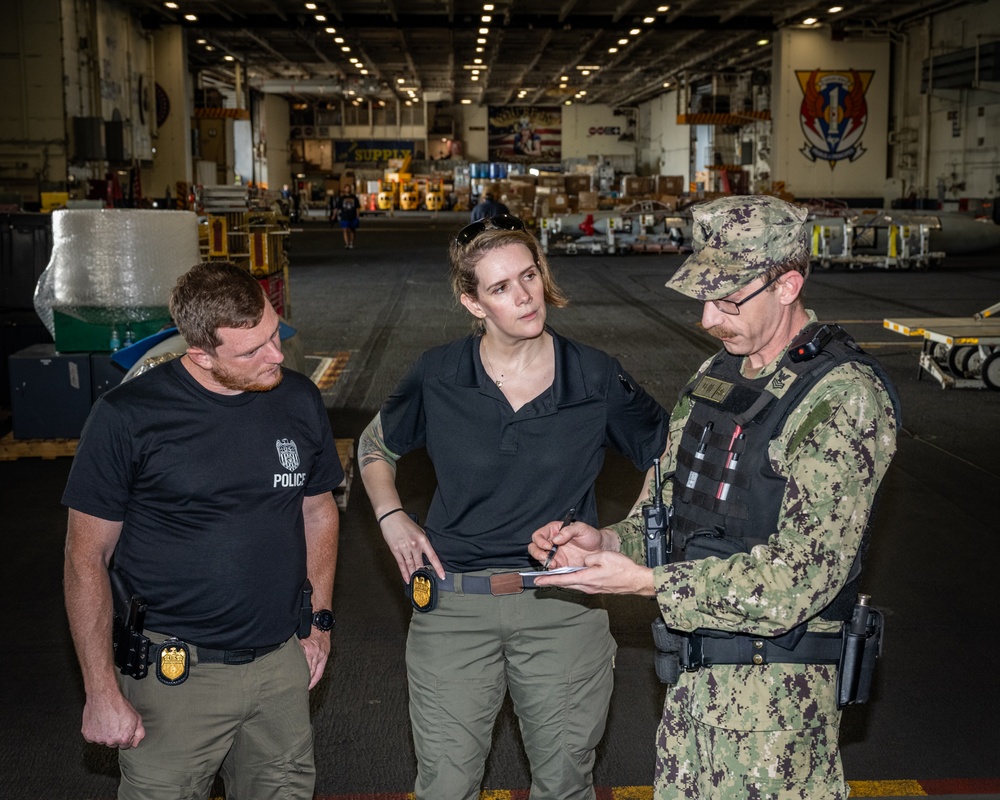 Naval Criminal Investigative Service (NCIS) Special Agents Afloat (SAA) Bernadette Duffy and Justin Botkin talk with Master-at-Arms First Class (MA!) Travis Beckman about an on-going investigation