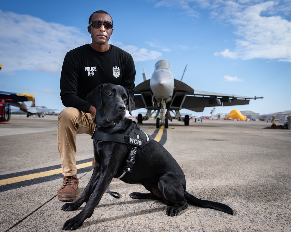 Naval Criminal Investigative Service (NCIS) Special Agent (SA) David Lawhorn and his K-9 companion Jill around the flight line with F-18 Hornets and the U. S. Navy's Flight Demonstration Team