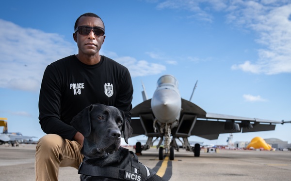 Naval Criminal Investigative Service (NCIS) Special Agent (SA) David Lawhorn and his K-9 companion Jill around the flight line with F-18 Hornets and the U. S. Navy's Flight Demonstration Team