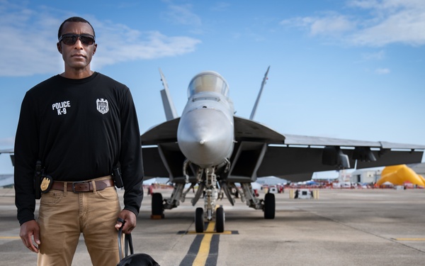 Naval Criminal Investigative Service (NCIS) Special Agent (SA) David Lawhorn and his K-9 companion Jill around the flight line with F-18 Hornets