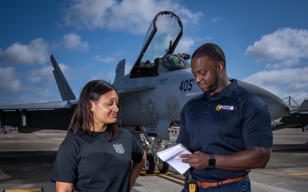 Naval Criminal Investigative Service (NCIS) Supervisory Special Agent (SSA) Jennifer Lynch and Special Agent (SA) Kenneth Randle discuss an on-going investigation around the flight line