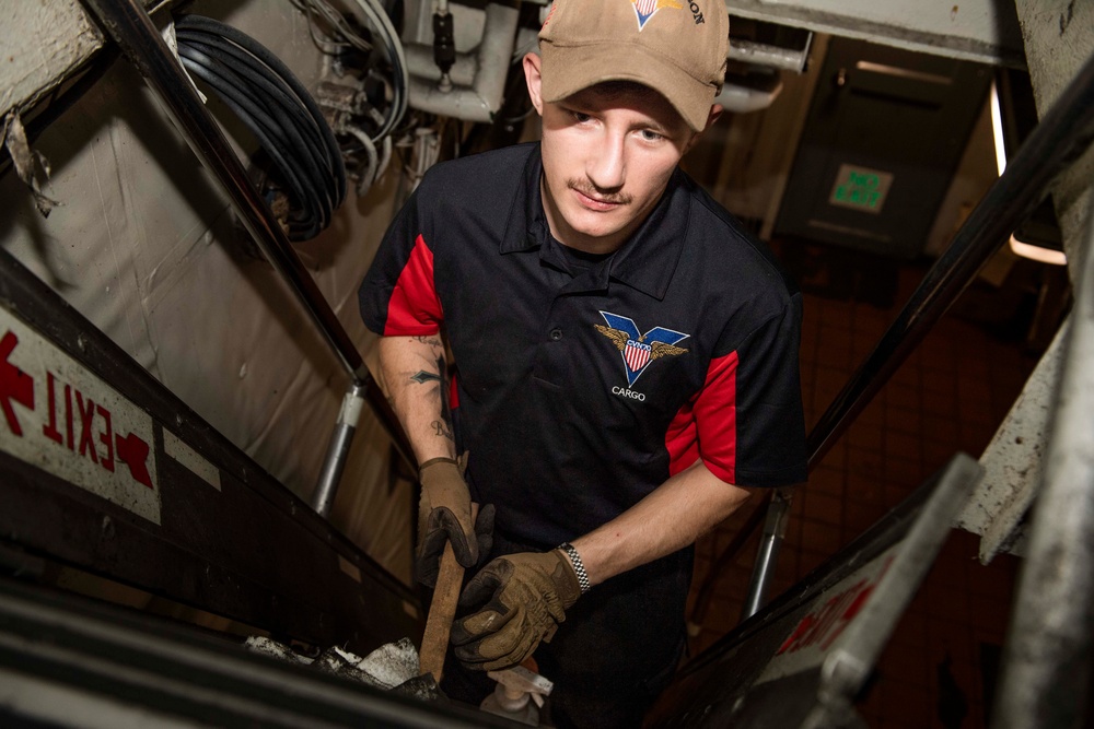 A Culinary Specialist cleans a ladder well