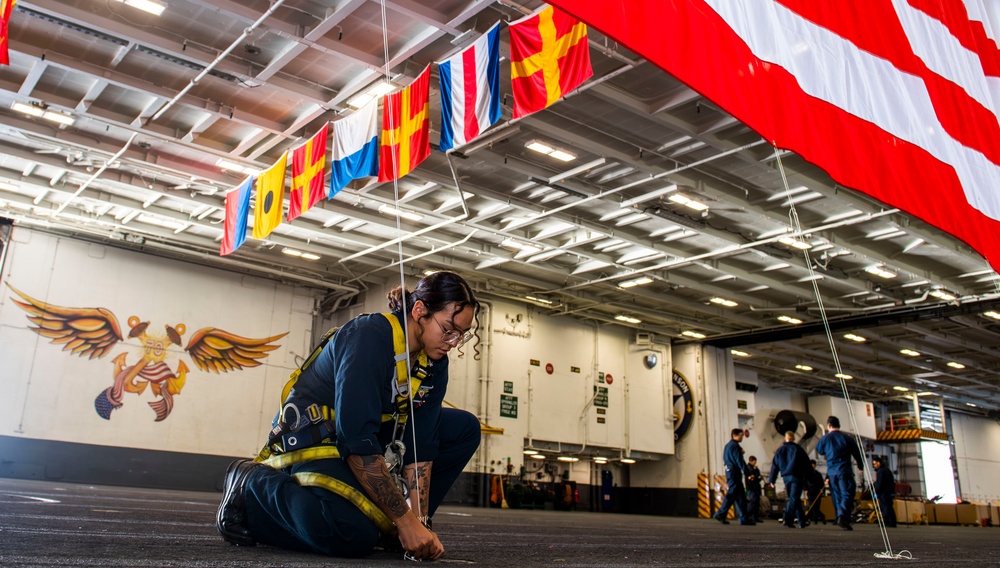 A Quartermaster secures the national ensign in the hangar bay aboard USS Carl Vinson (CVN 70)