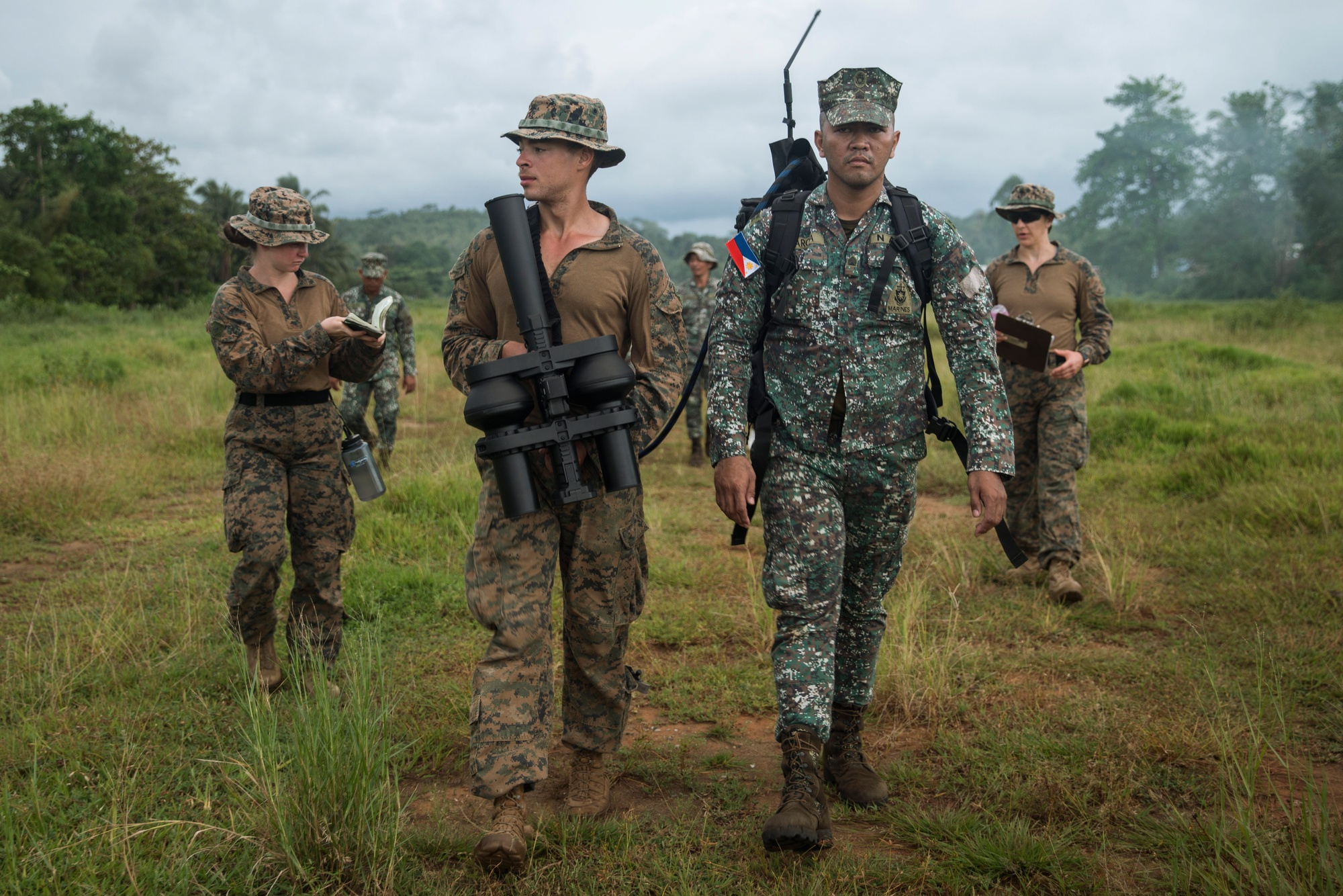 A US Marine and a Philippine Marine walk to a firing point carrying a NightFighter S counter-UAS effector during exercise KAMANDAG 8 in Palawan Province, Philippines, October 2024.