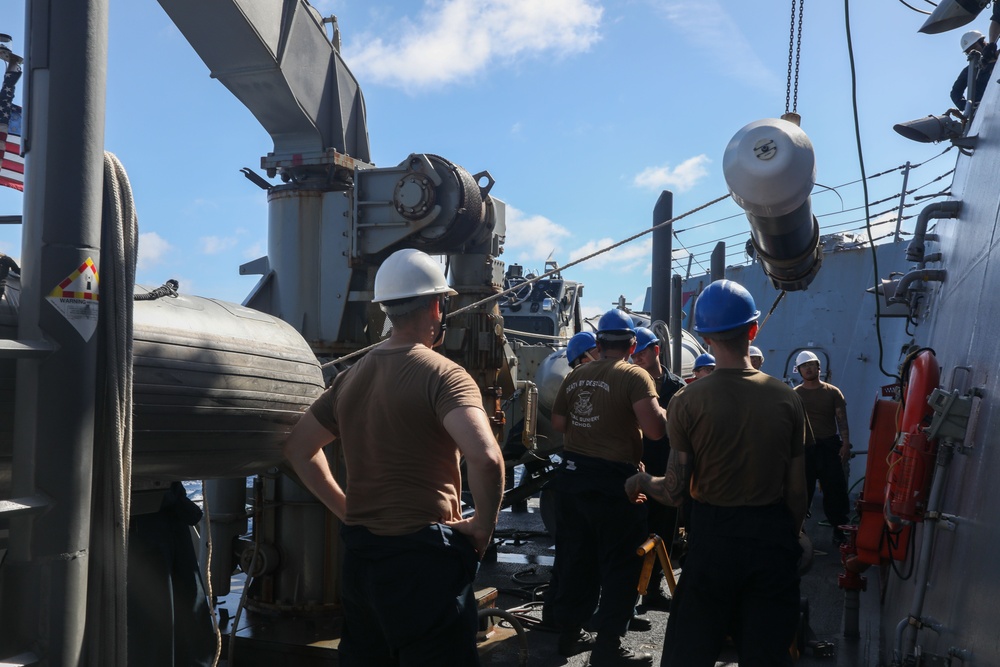 Sailors aboard the USS Howard conduct a torpedo download in the South China Sea
