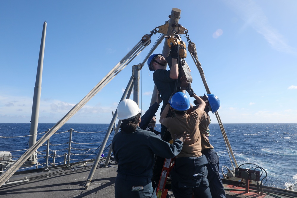 Sailors aboard the USS Howard conduct a torpedo download in the South China Sea