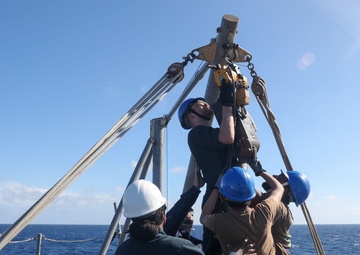 Sailors aboard the USS Howard conduct a torpedo download in the South China Sea