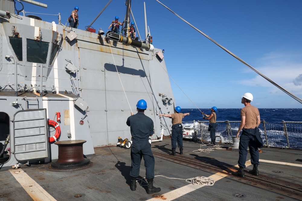 Sailors aboard the USS Howard conduct a torpedo download in the South China Sea