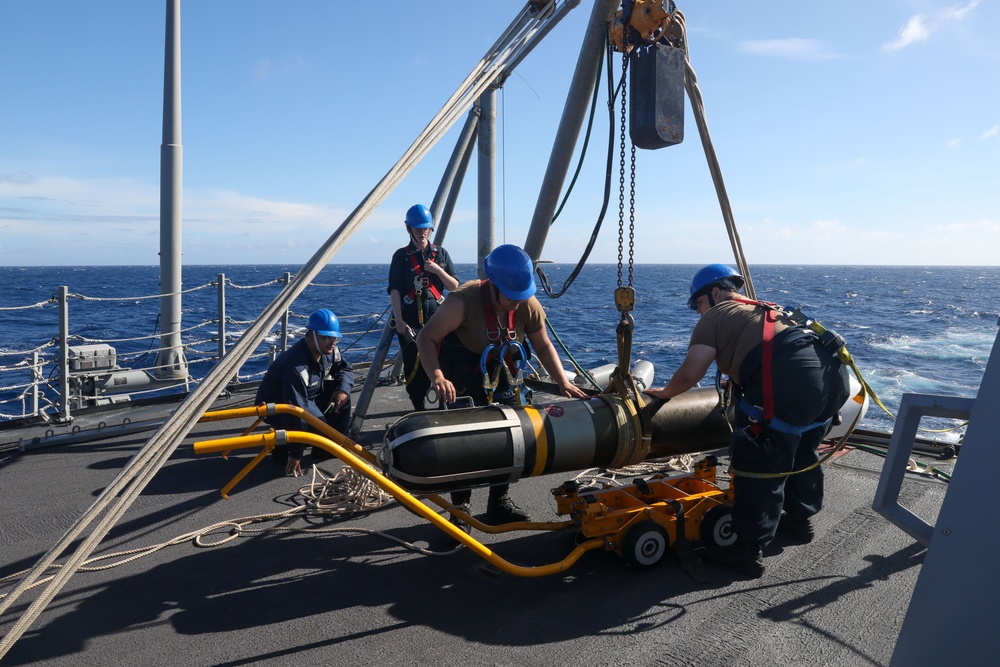 Sailors aboard the USS Howard conduct a torpedo download in the South China Sea