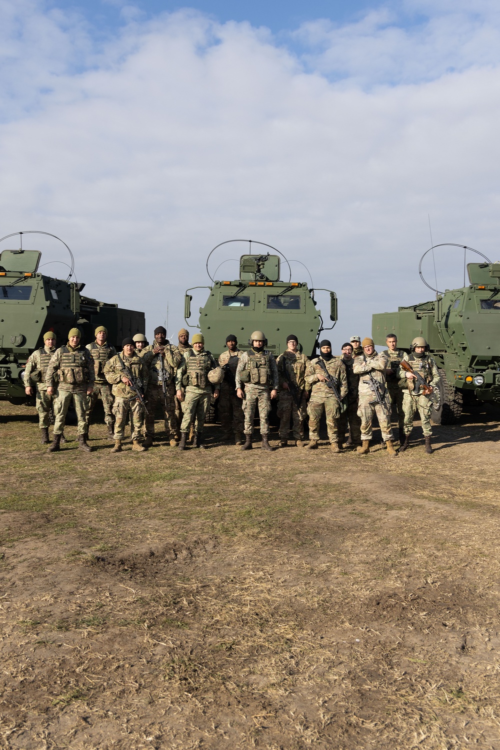 U.S. Soldiers and Romanian soldiers pose in front of HIMARS