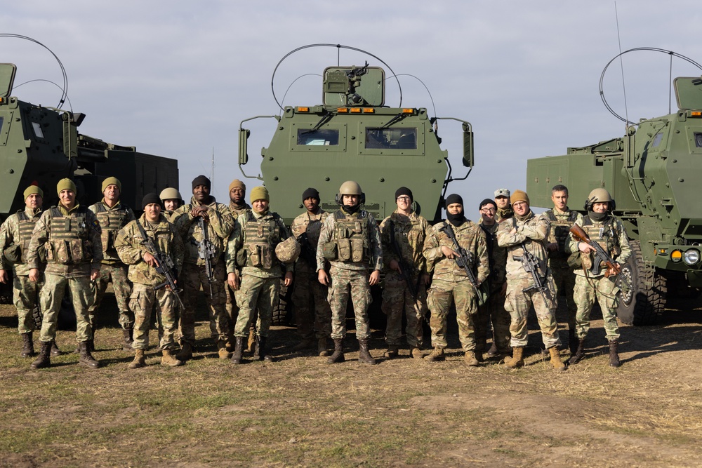 U.S. Soldiers and Romanian soldiers pose in front of HIMARS