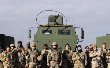 U.S. Soldiers and Romanian soldiers pose in front of HIMARS