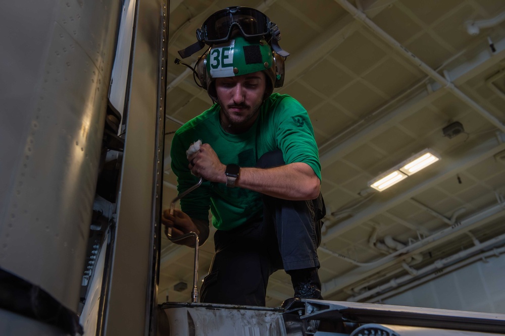 Sailor conducts aircraft maintenance in the hangar bay of USS Carl Vinson (CVN 70)