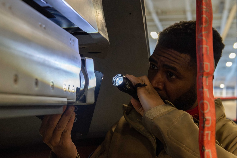 Sailor conducts aircraft maintenance in the hangar bay of USS Carl Vinson (CVN 70)