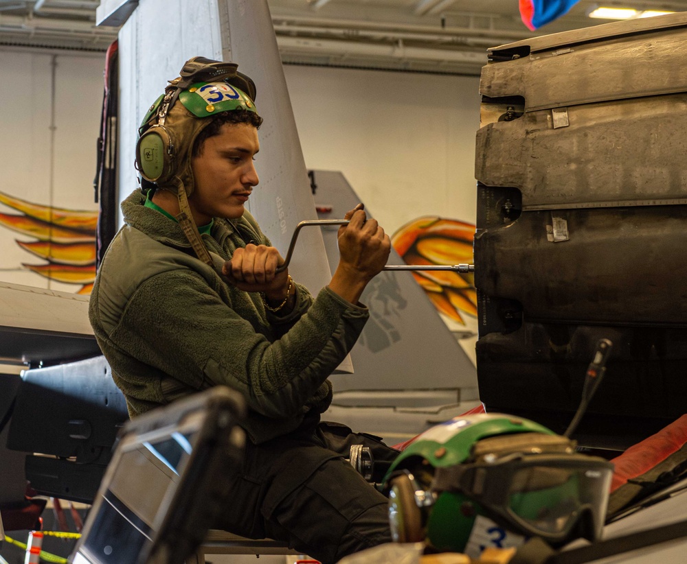 Sailor conducts aircraft maintenance in the hangar bay of USS Carl Vinson (CVN 70)